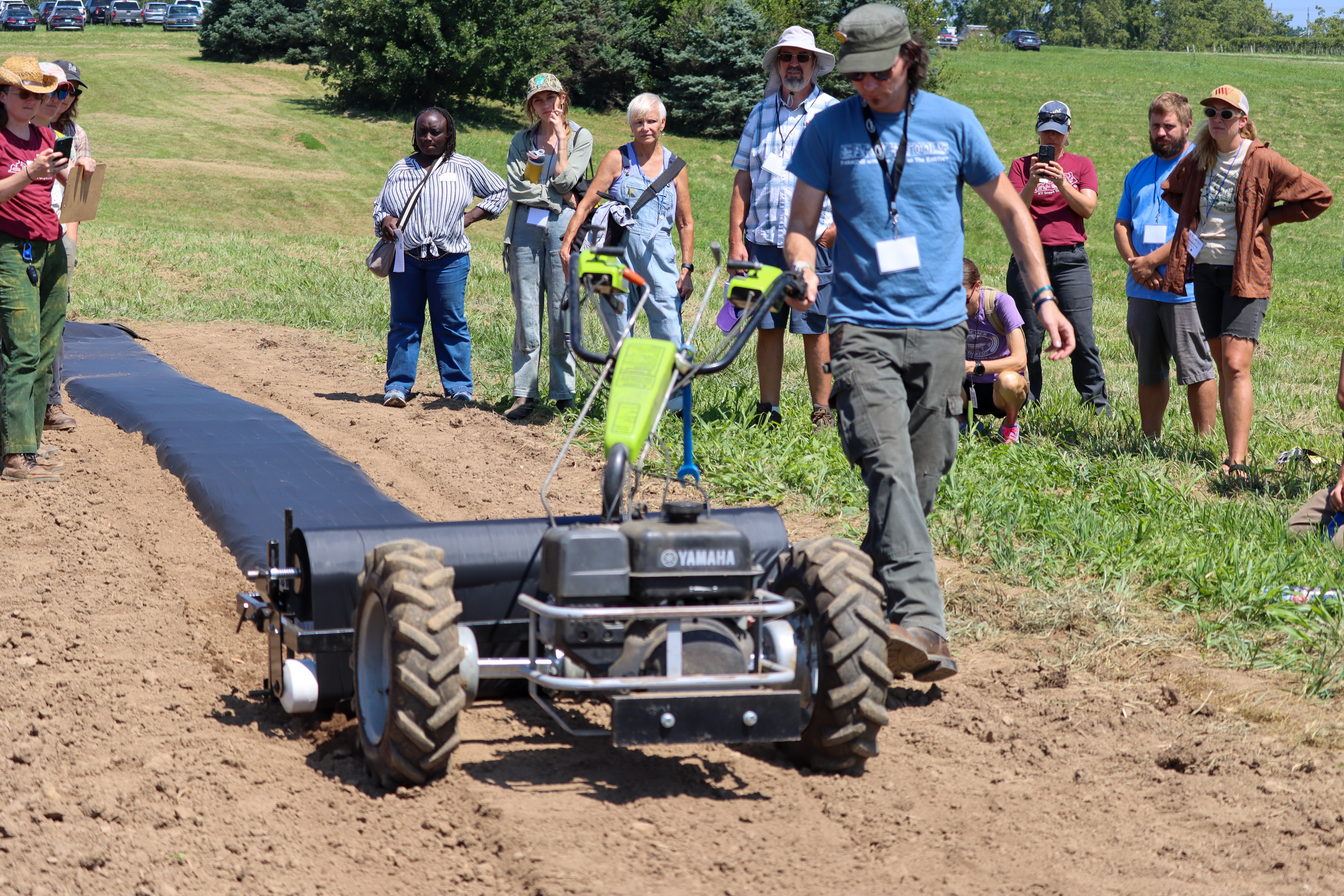 Man in field walking beside 2-wheel tractor