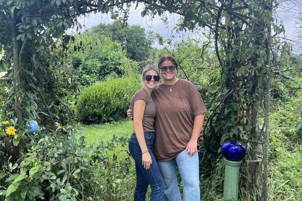 two people standing under a plant covered arch