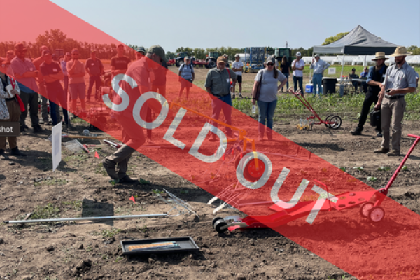 person pushing a small weeding implement with others watching. Banner overlay in read reading "sold out"