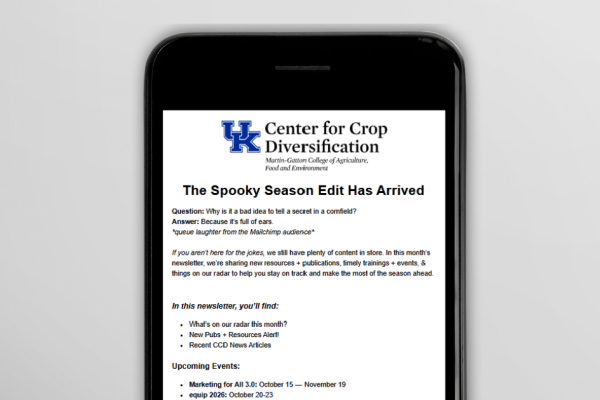 Smartphone displaying a University of Kentucky Center for Crop Diversification newsletter titled “The Spooky Season Edit Has Arrived,” featuring a seasonal cornfield joke, an introduction to the October newsletter, and a list of resources and upcoming events.