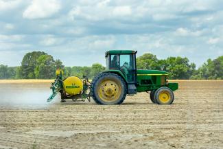 tractor spraying field blue sky