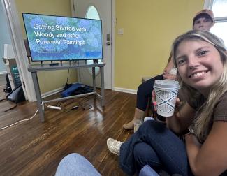 person holding a cup smiling with television in the background