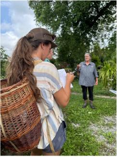 person with basket on back in front of other person in front of tree