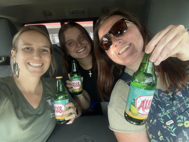 three people smiling and holding soft drink bottles