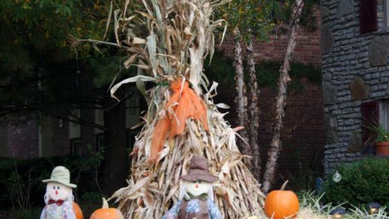 corn shock display with hay bales, pumpkins, and scarecrow