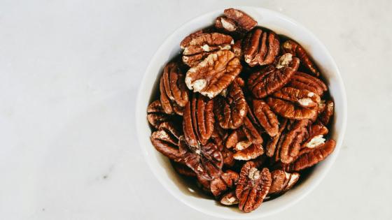 cup of pecans on white table