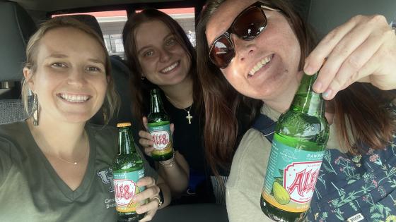 three people smiling and holding soft drink bottles