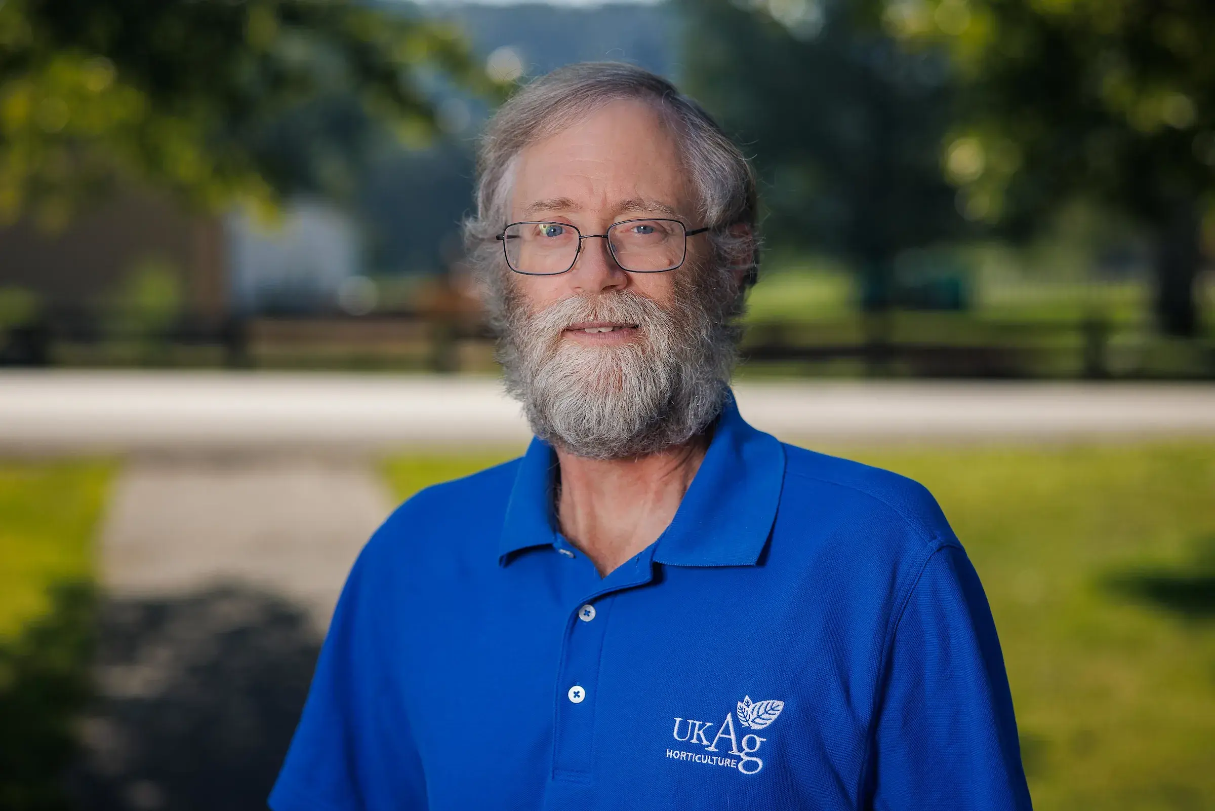 man in blue shirt standing in front of grass and concrete